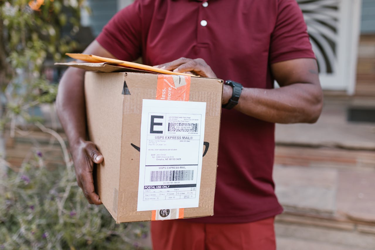 services-06 Close-up of a courier delivering a parcel with USPS express mail label outdoors.